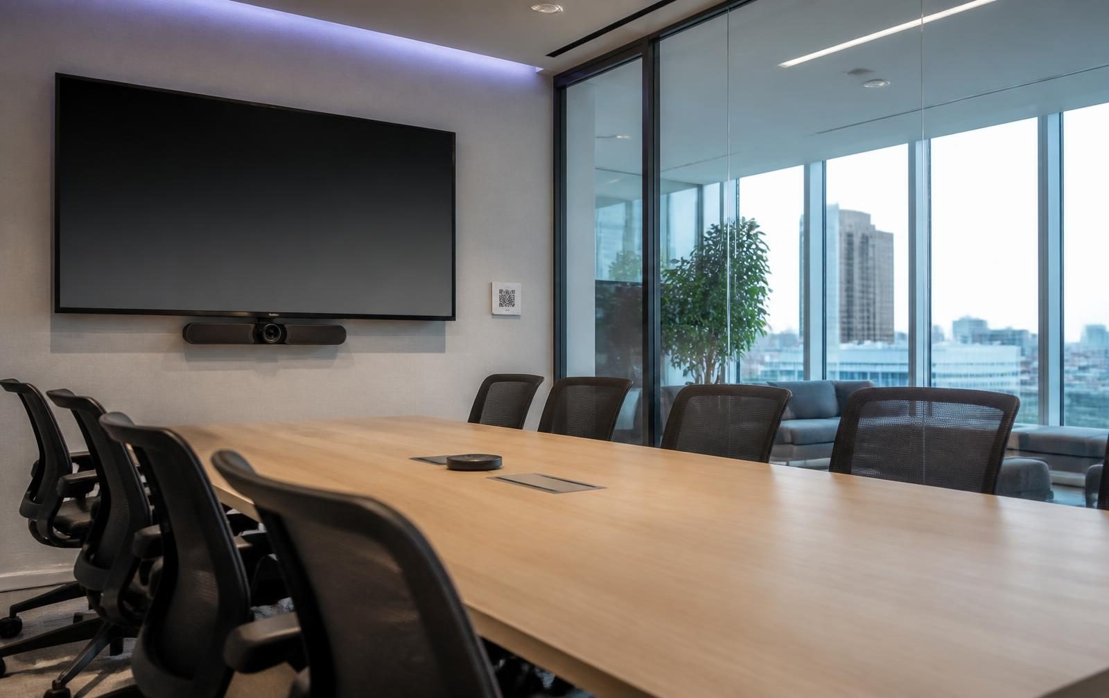 Meeting room with a wall-mounted display, video bar and a QR code plate beside it